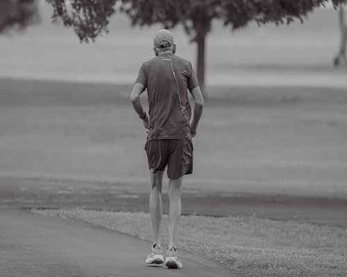 Active senior person jogging in the park morning light